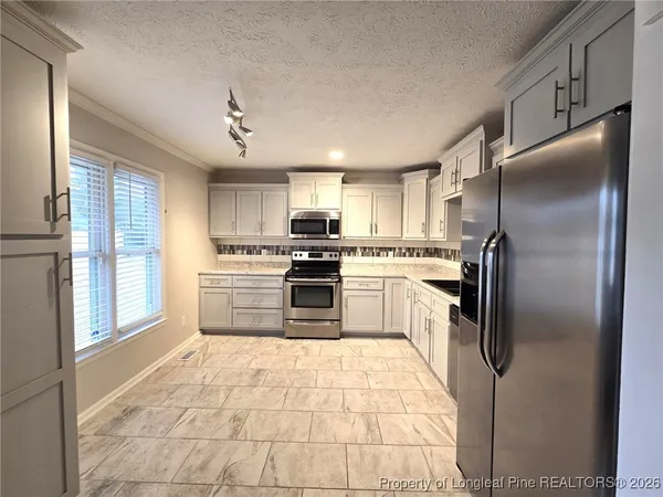 a kitchen with granite countertop a refrigerator and a stove top oven