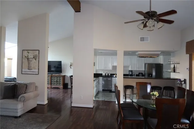 a kitchen with stainless steel appliances granite countertop a stove top oven a refrigerator a dining table and chairs with wooden floor