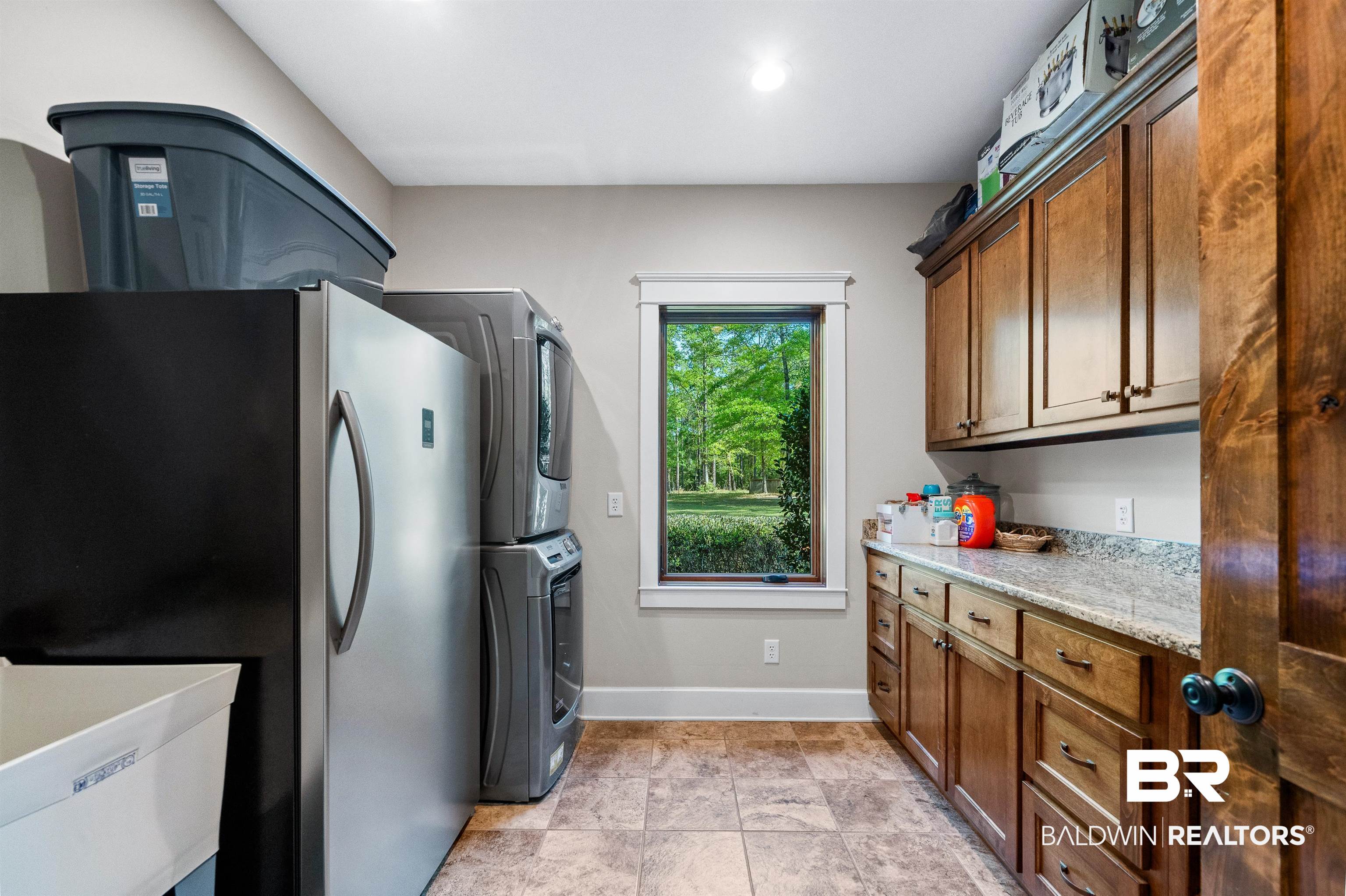 47252 Emmons Road Bay Minette, AL 36507 - Photo 25 of 50 Kitchen featuring freestanding refrigerator, stacked washer / drying machine, wood finish cabinetry, and light stone counters