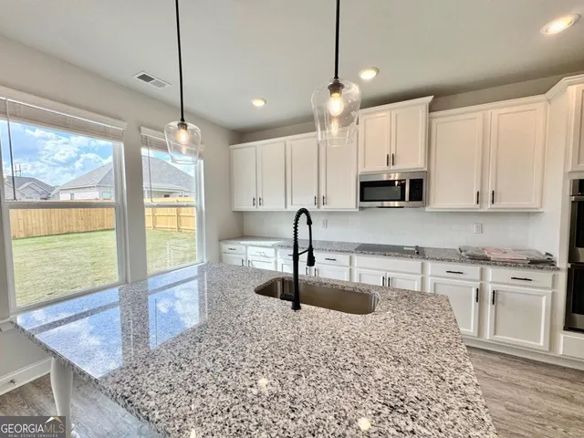 a kitchen with stainless steel appliances granite countertop a sink a stove top oven a counter space and cabinets