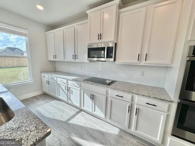 a kitchen with stainless steel appliances granite countertop a stove a sink and a microwave
