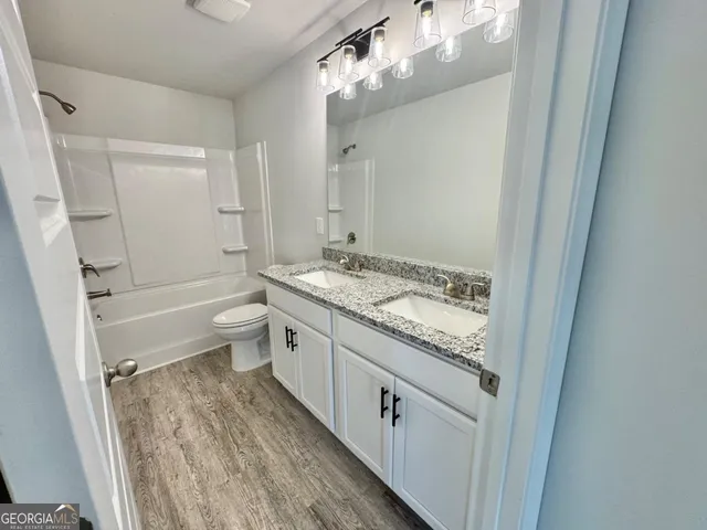 a bathroom with a granite countertop sink a toilet a mirror and shower