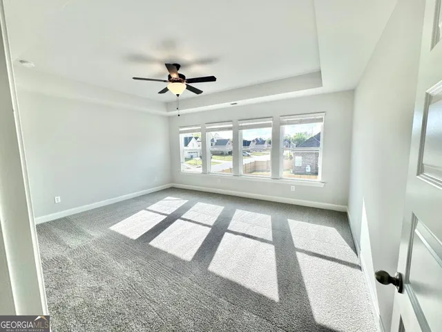 an empty room with windows and ceiling fan