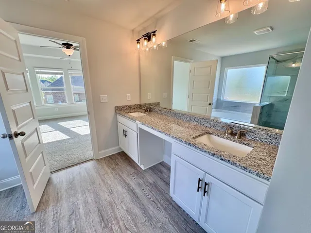 a bathroom with a granite countertop sink a mirror and shower