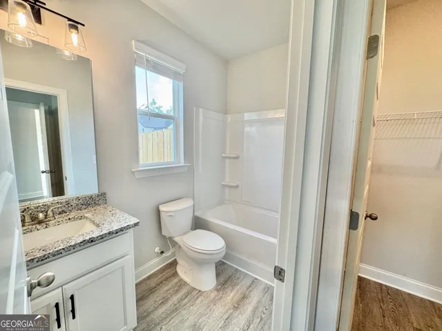a bathroom with a granite countertop toilet a sink and a mirror