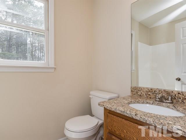 9312 Tallgrass Road Raleigh, NC 27603 - Photo 16 of 18 a bathroom with a granite countertop toilet a sink and a mirror