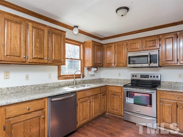 9312 Tallgrass Road Raleigh, NC 27603 - Photo 7 of 18 a kitchen with granite countertop wooden cabinets and a stove top oven