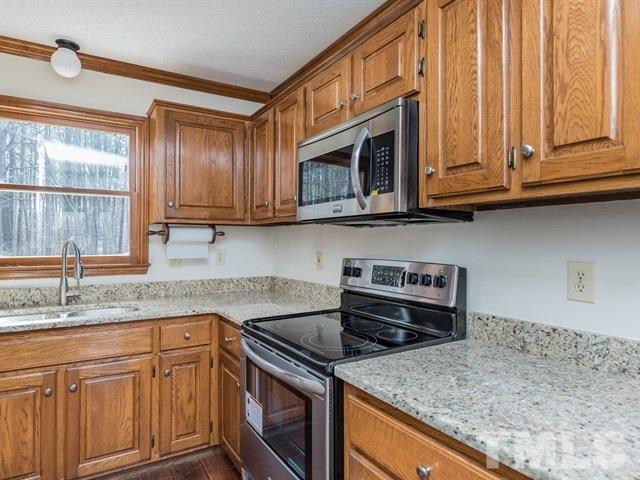 9312 Tallgrass Road Raleigh, NC 27603 - Photo 8 of 18 a kitchen with stainless steel appliances granite countertop a sink a stove and cabinets
