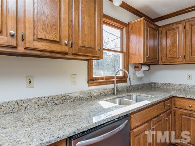 9312 Tallgrass Road Raleigh, NC 27603 - Photo 9 of 18 a kitchen with granite countertop a sink a window and cabinets