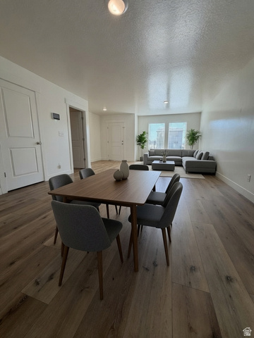 3831 South Powderwood Lane Mapleton, UT 84664 - Photo 6 of 17 Open-concept living area featuring wood-finish flooring throughout, a dining table with seating for four, and a sectional sofa arrangement Thank you to AI for the photographic possibility.