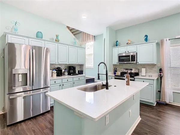 a kitchen with stainless steel appliances kitchen island granite countertop a dining table chairs and refrigerator