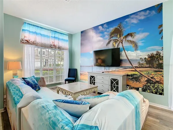 a living room with furniture a flat screen tv and a floor to ceiling window