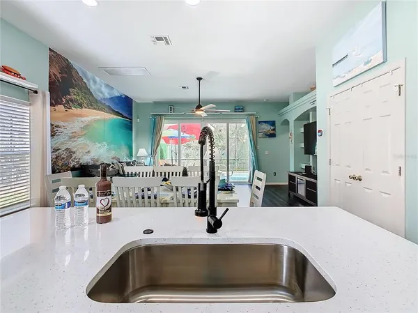 a kitchen with a sink a counter top space and living room view