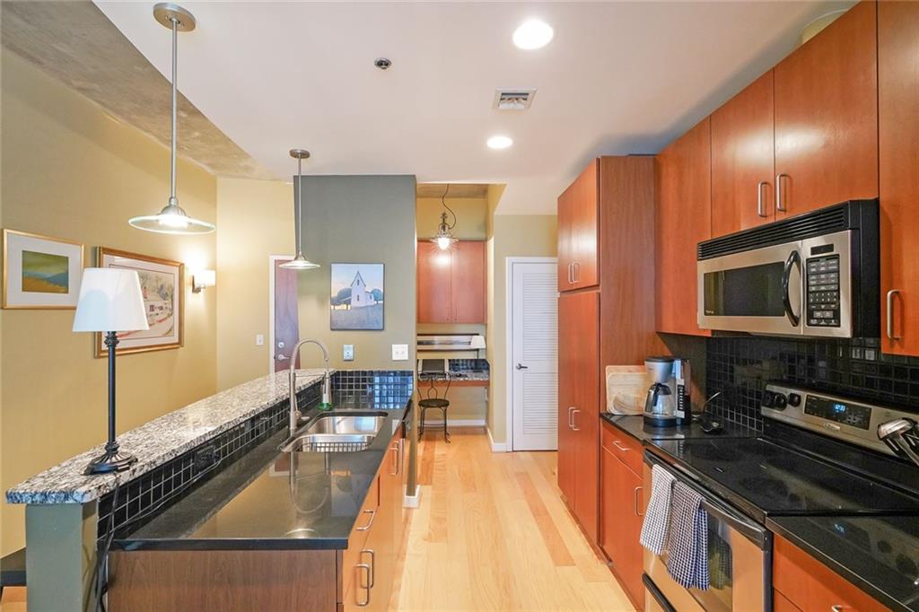 a large kitchen with stainless steel appliances a stove a sink dishwasher and cabinets with wooden floor