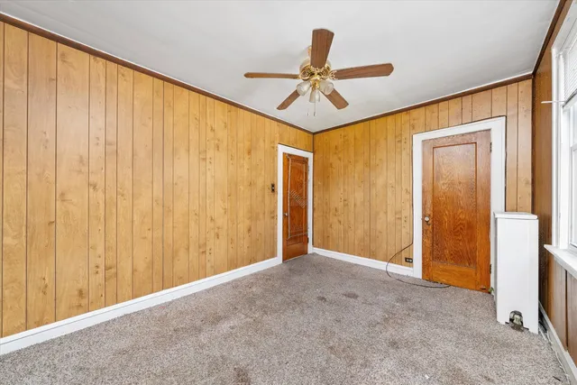 a view of an empty room and chandelier fan