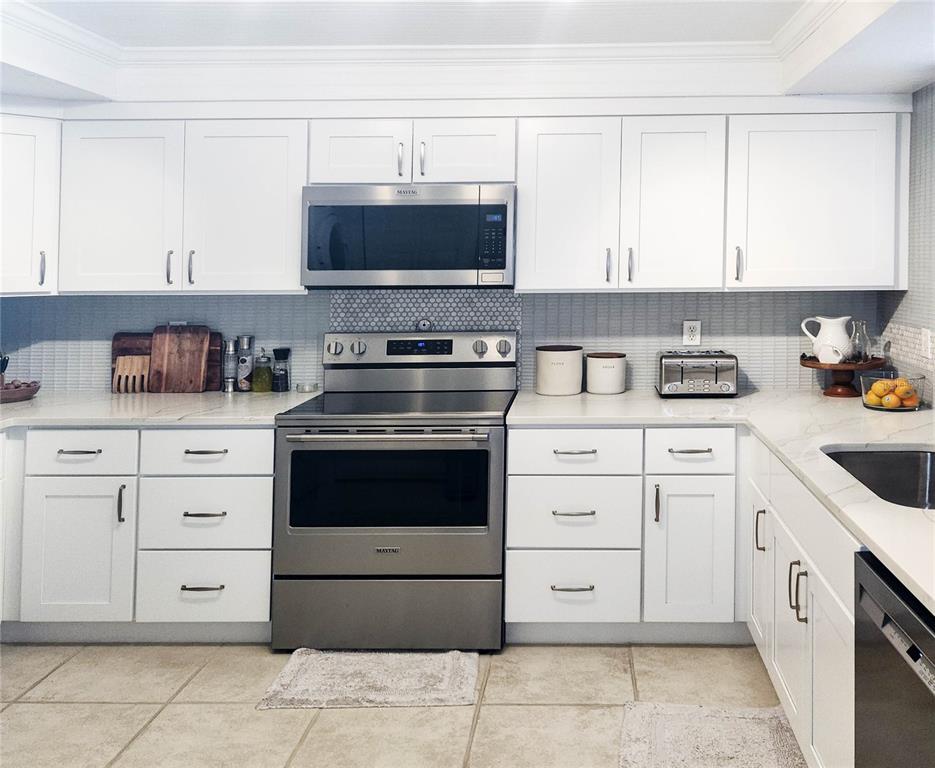 5052 Marsh Field Road, Unit 9 Sarasota, FL 34235 - Photo 3 of 15 a kitchen with white cabinets and stainless steel appliances