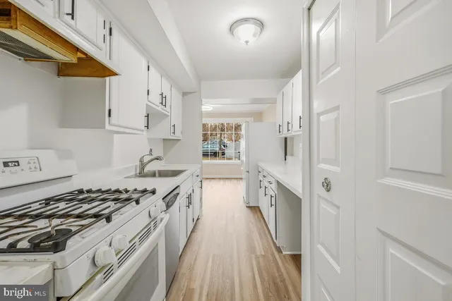 a kitchen with stainless steel appliances a stove and white cabinets