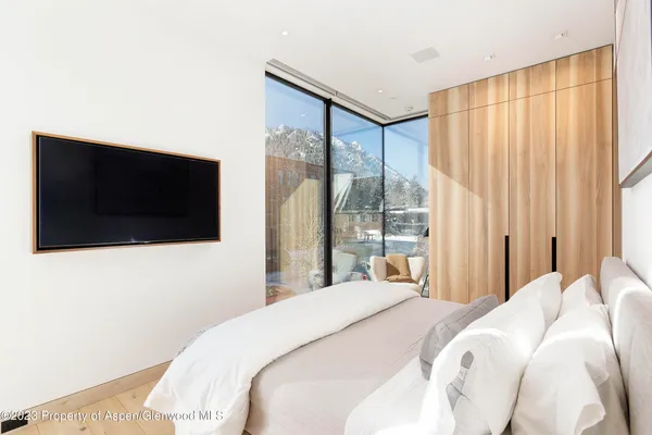 a bedroom with a large bed and a flat tv screen next to a window