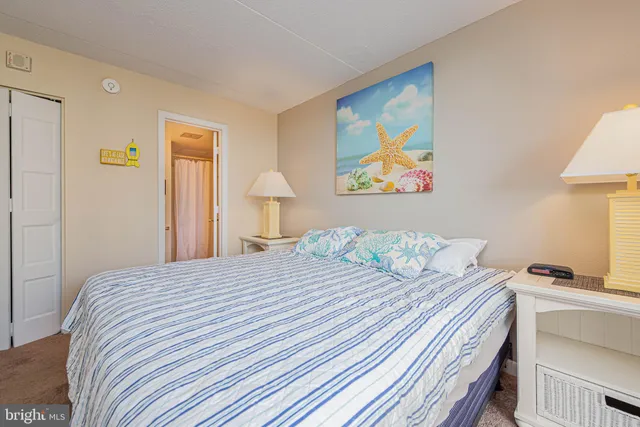 a bedroom with a bed and a lamp on dresser