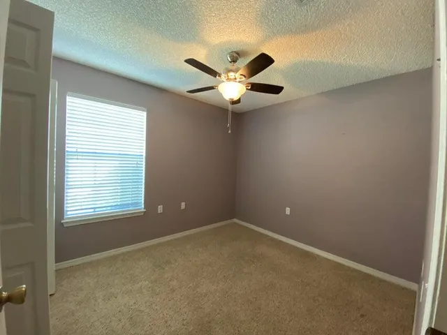 an empty room with windows and fan
