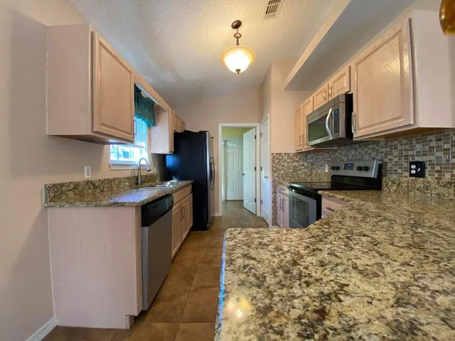 a kitchen with stainless steel appliances granite countertop a sink stove and cabinets