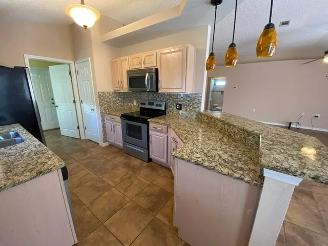 a kitchen with kitchen island granite countertop a sink stove and refrigerator