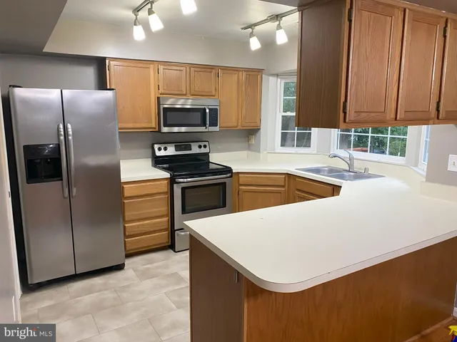 a kitchen with stainless steel appliances a refrigerator a sink a stove a microwave and island