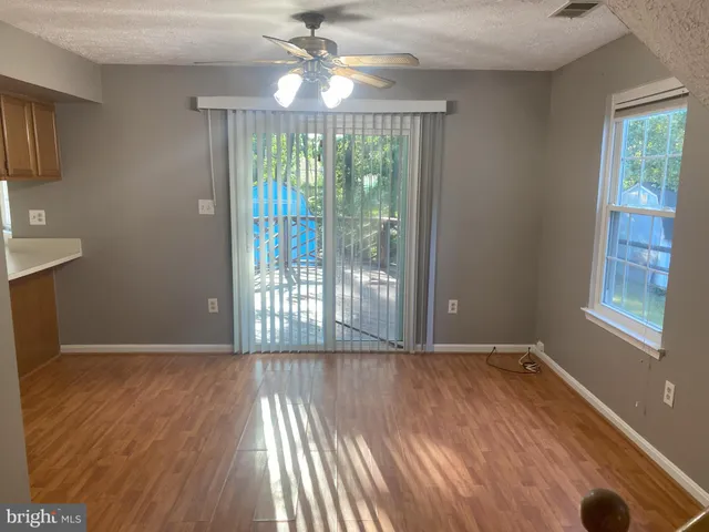 a view of an empty room with glass door and wooden floor