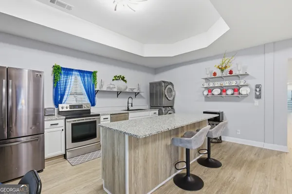 a large kitchen with granite countertop a sink and dishwasher a stove top oven with wooden floor