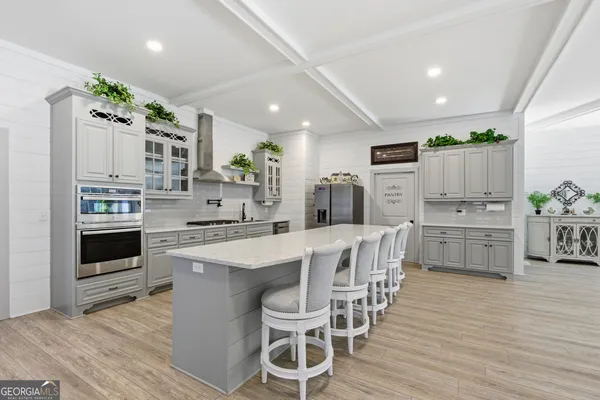 a kitchen with stainless steel appliances a white table chairs and a refrigerator
