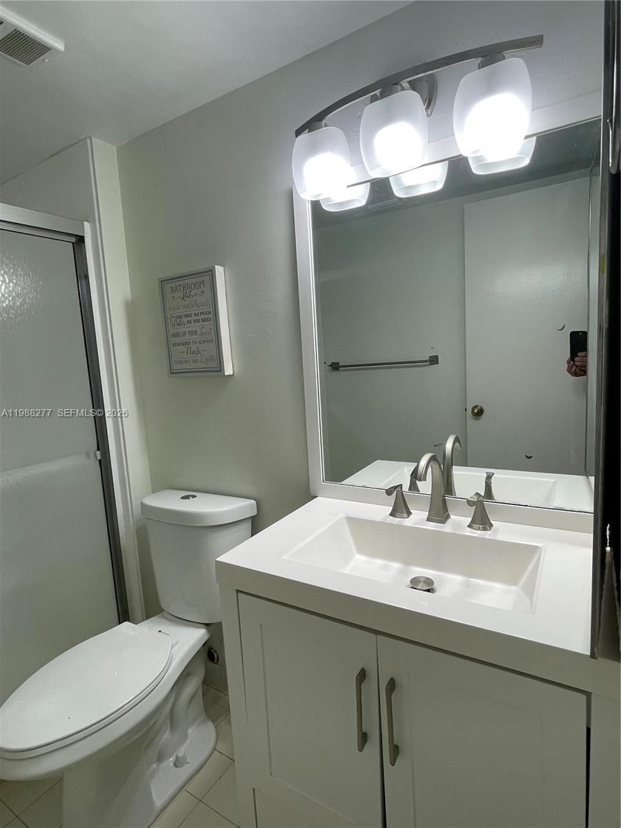 8871 Wiles Road, Unit 105 Coral Springs, FL 33067 - Photo 14 of 43 a bathroom with a sink mirror and toilet
