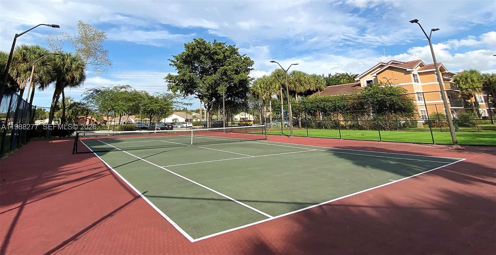 8871 Wiles Road, Unit 105 Coral Springs, FL 33067 - Photo 36 of 43 a view of a tennis ground with large trees