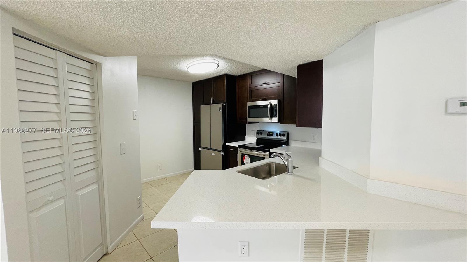 8871 Wiles Road, Unit 105 Coral Springs, FL 33067 - Photo 8 of 43 a kitchen with a sink and a refrigerator