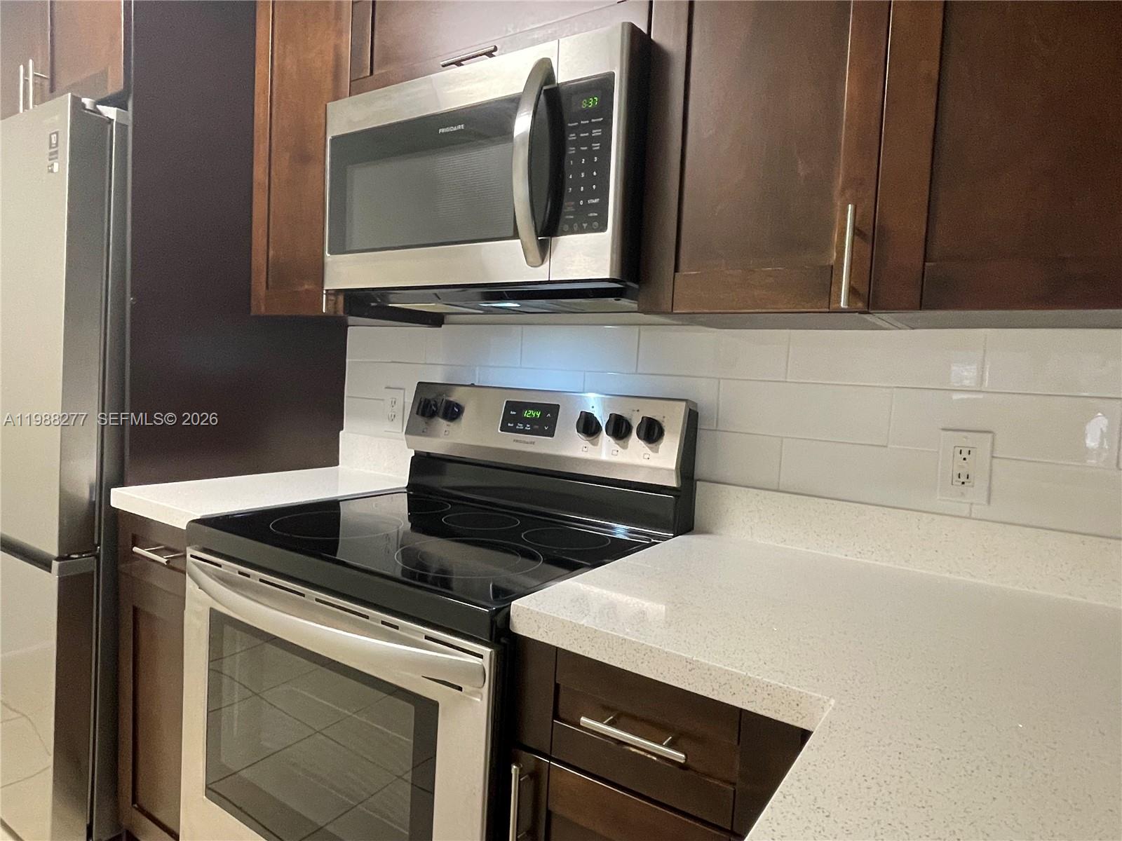 8871 Wiles Road, Unit 105 Coral Springs, FL 33067 - Photo 9 of 43 a kitchen with granite countertop a stove and a microwave