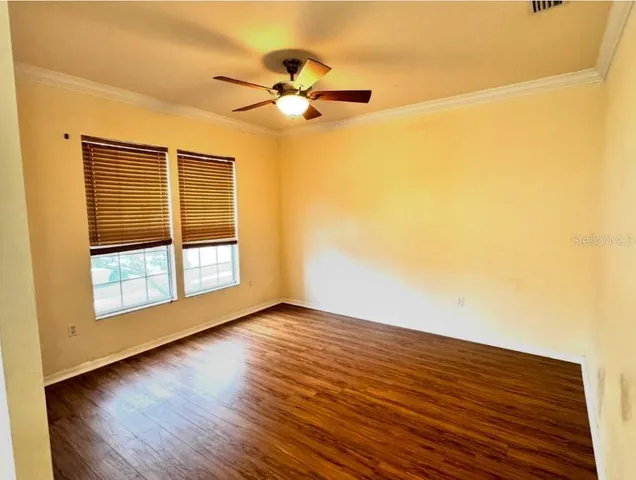 a view of empty room with wooden floor and fan