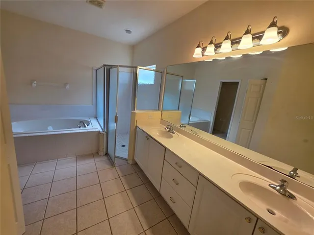 a spacious bathroom with a double vanity sink a large mirror and a bathtub