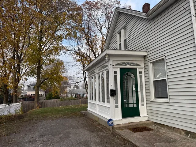 a view of a white house with a large tree