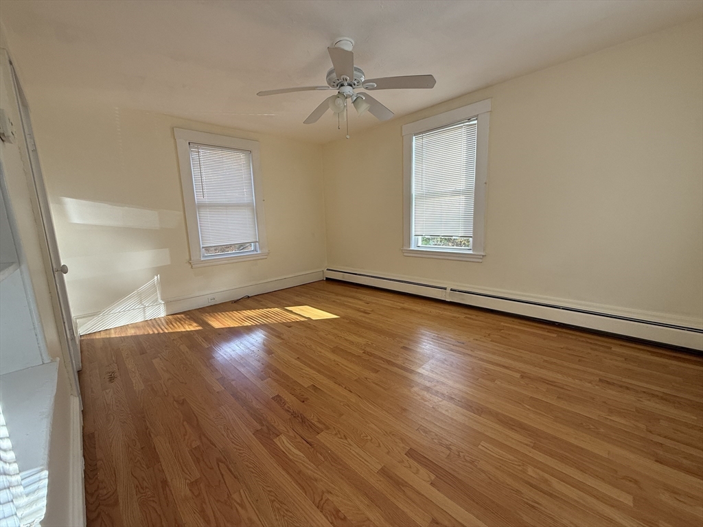 314 Webster Street, Unit B Needham, MA 02494 - Photo 7 of 14 an empty room with wooden floor fan and windows