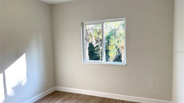 a view of an empty room with wooden floor and a window