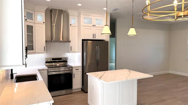 a kitchen with stainless steel appliances kitchen island a refrigerator sink and stove