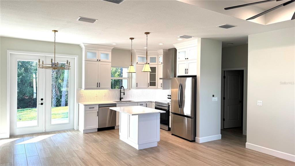 4884 Kisla Rd Port North Port, FL 34288 - Photo 18 of 19 a kitchen with stainless steel appliances kitchen island granite countertop a refrigerator and a wooden floor
