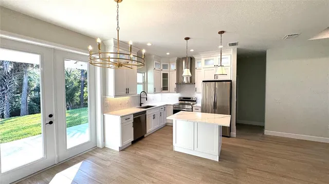 a large kitchen with kitchen island a large counter top space a sink stainless steel appliances and cabinets