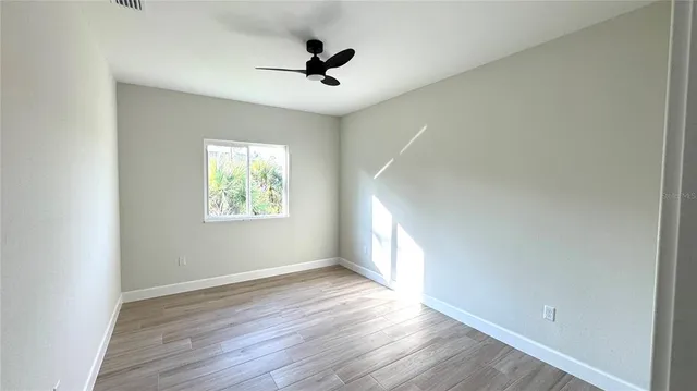 a view of empty room with wooden floor and fan