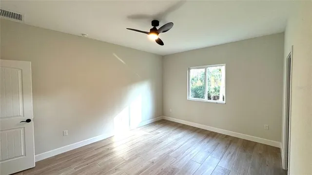 a view of an empty room with wooden floor and a window