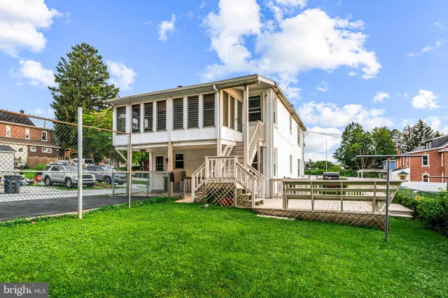 a view of a white house with a big yard and large trees