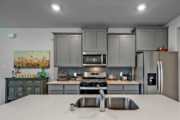 a kitchen with stainless steel appliances granite countertop a refrigerator a stove top oven a sink dishwasher and white cabinets with wooden floor