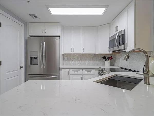 a kitchen with stainless steel appliances a refrigerator sink and microwave