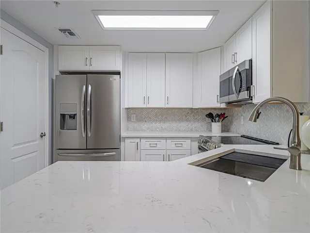 a kitchen with stainless steel appliances a refrigerator sink and microwave