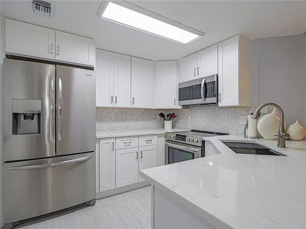 a kitchen with refrigerator a microwave and sink