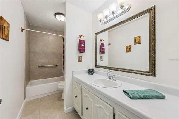 a bathroom with a granite countertop sink a mirror a bathtub and shower